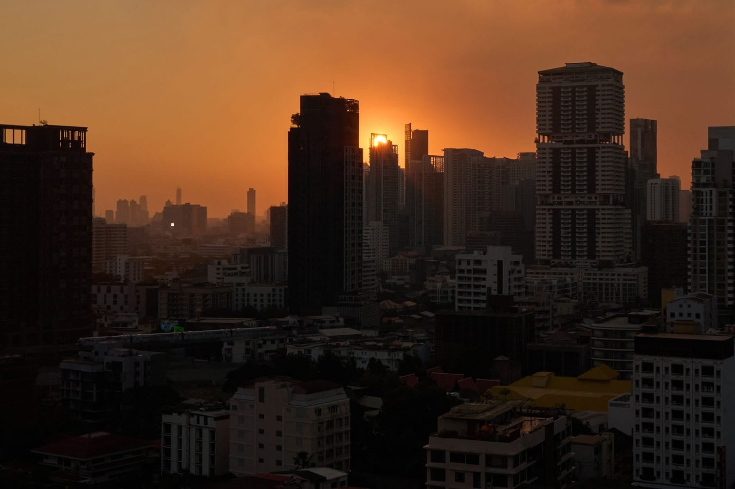 A general view shows the sun setting beyond the skyline of Bangkok